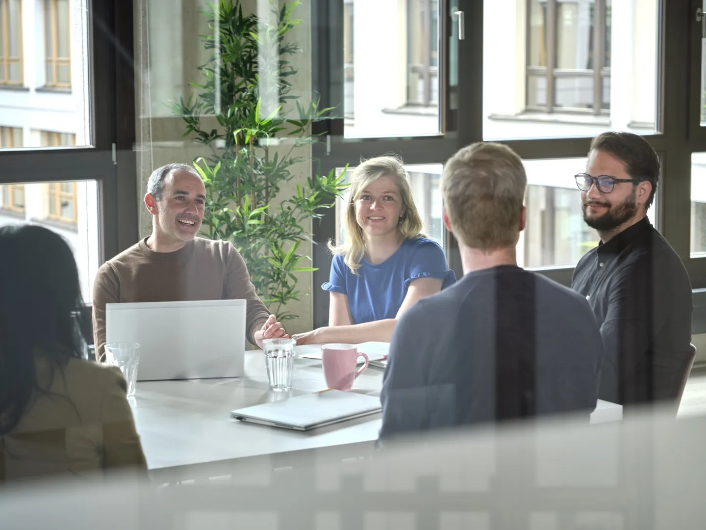 Mitarbeiter der Mercedes-Benz Group Services unterhalten sich an einem Tisch