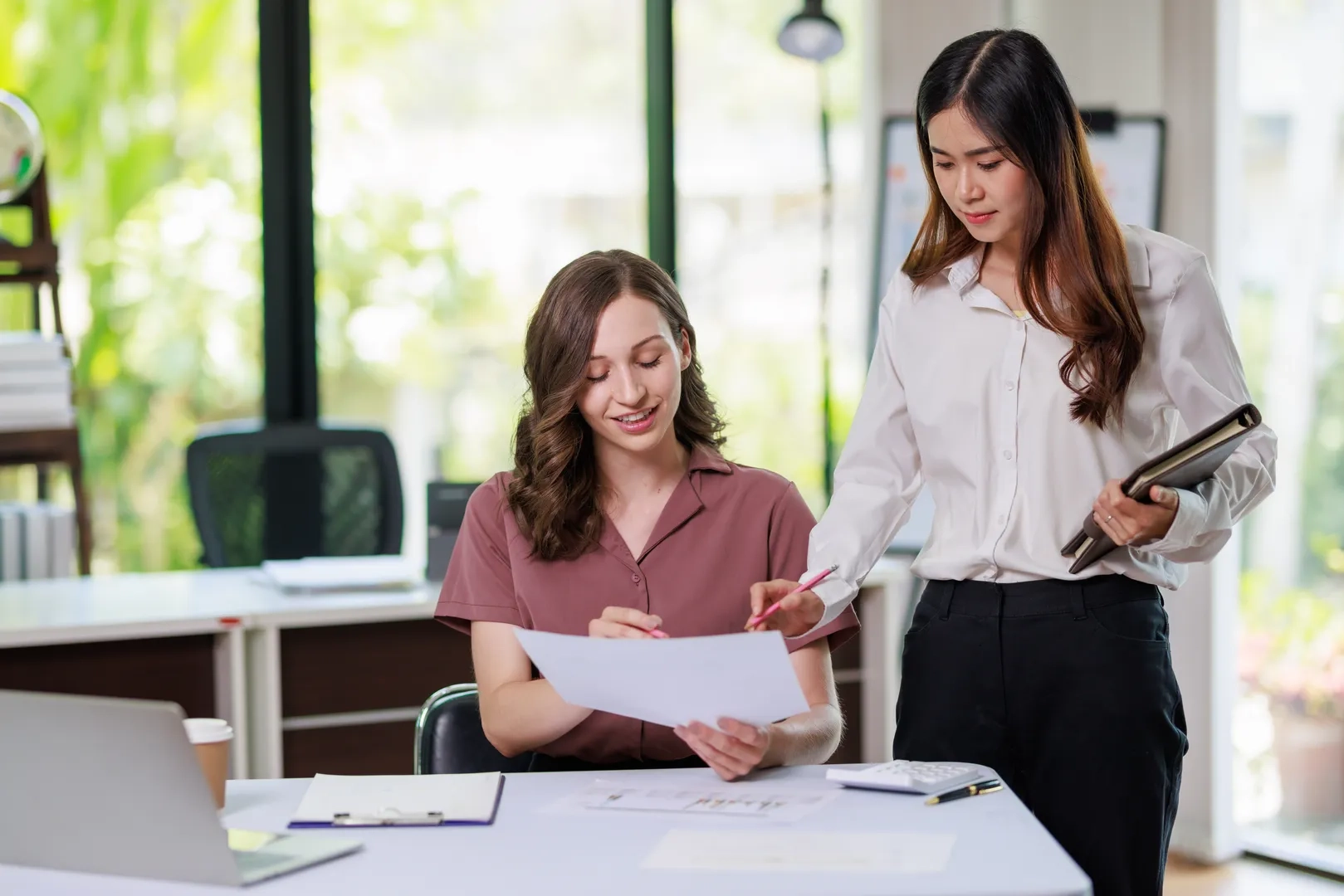 Zwei Mitarbeiterinnen unterhalten sich über ein Dokument